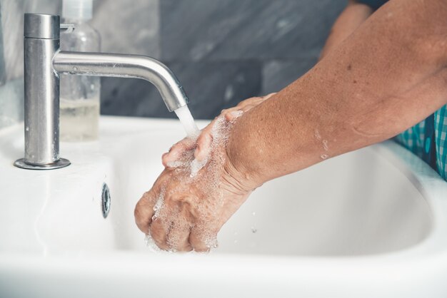 Donna anziana lavarsi le mani per la prevenzione della nuova malattia da coronavirus 2019 o covid-19