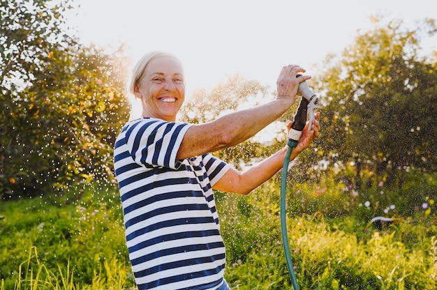 Senior donna che innaffia le piante in giardino