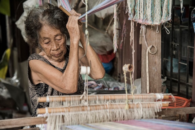 Photo senior woman weaving loom in factory