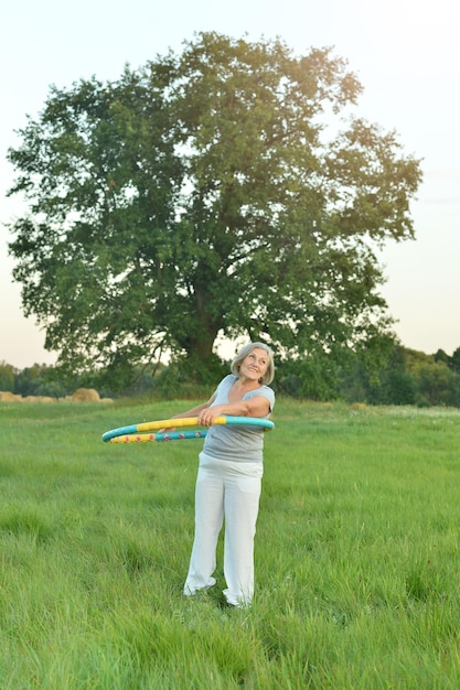 Senior woman wih hula hoop in the park