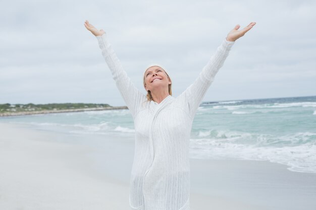 Senior woman with arms outstretched at beach