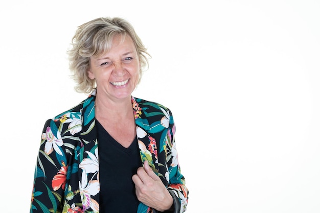 Senior woman with blond hair with her hand on her floral fashion vest with blue eyes on white background