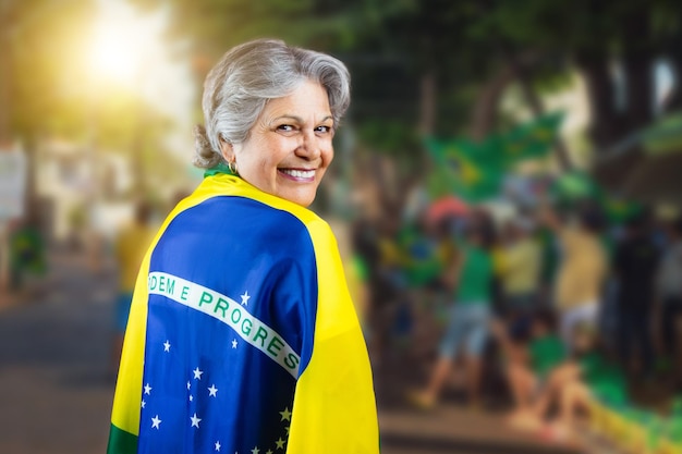 Senior Woman With Brazil Flag on Bokeh Background cheering for Brazil to be the champion