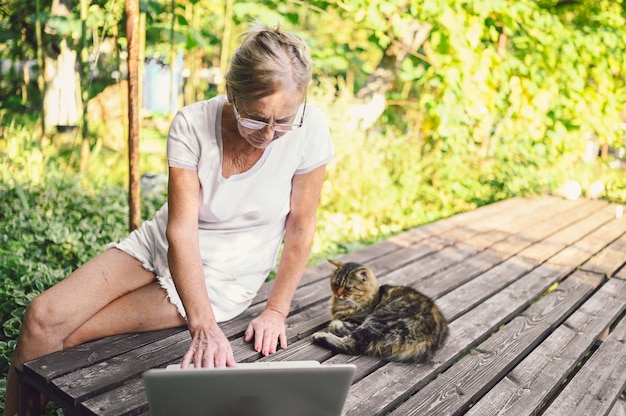 Senior woman with cat working on laptop