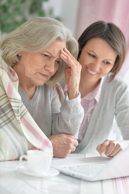 Senior woman with daughter  with laptop and tea