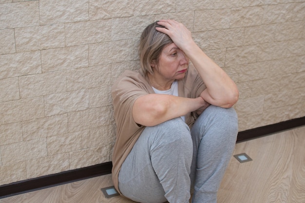 Senior woman with depression stress sad sitting on the\
floor.