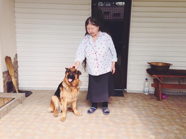 Foto donna anziana con il cane alla porta d'ingresso