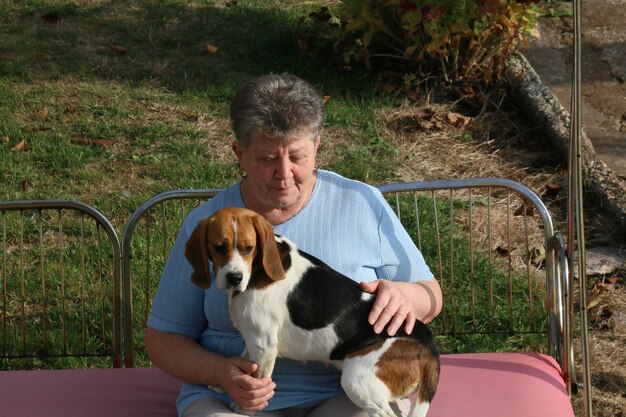 Foto donna anziana con un cane seduta in un parco pubblico