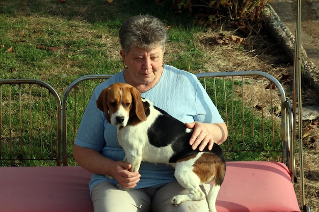 公共の公園に犬を連れて座っている年配の女性