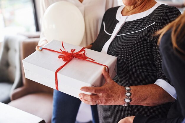 Senior woman with family and friends celebrating a birthday\
indoors.