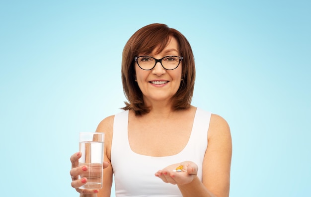 senior woman with glass of water and pills