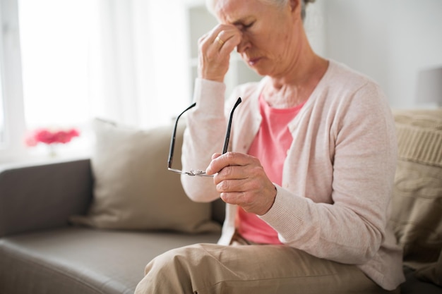 Photo senior woman with glasses having headache at home