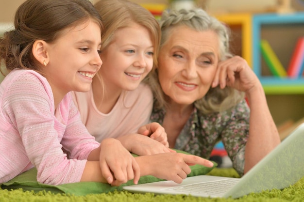 Senior woman with granddaughters using laptop