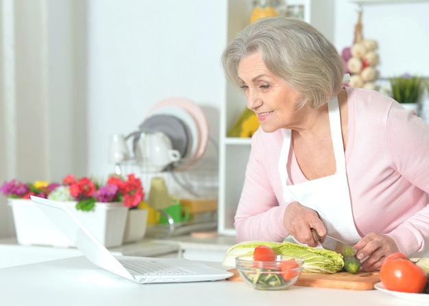 Senior woman with grey hair cooking in kitchen