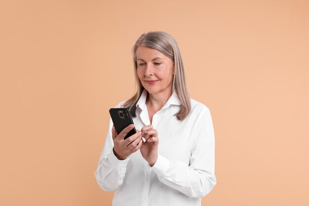 senior woman with phone on beige background