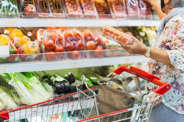 Senior donna con una maschera protettiva in un supermercato