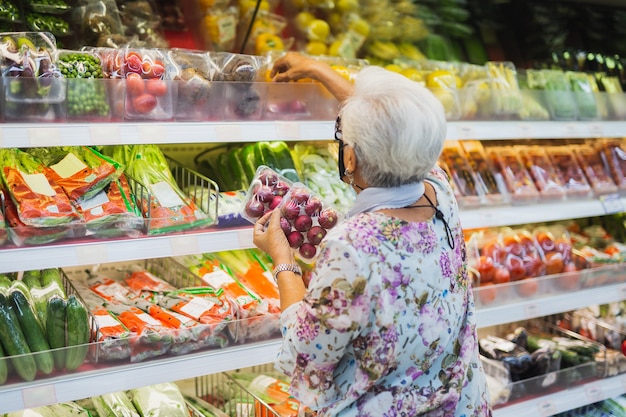 Senior donna con una maschera protettiva in un supermercato