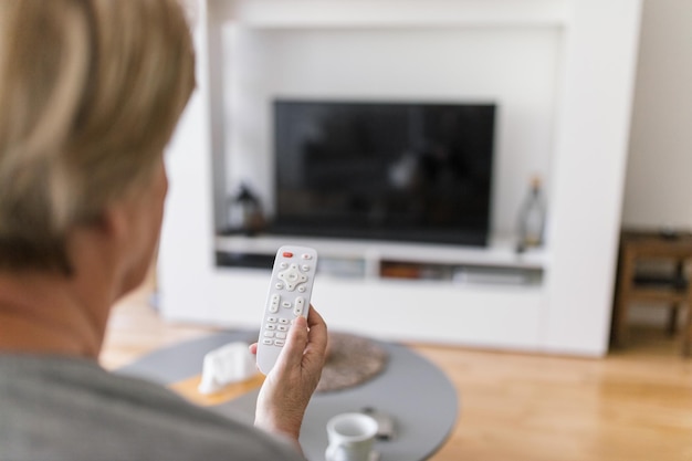 リモコンを持ってテレビを見る年配の女性