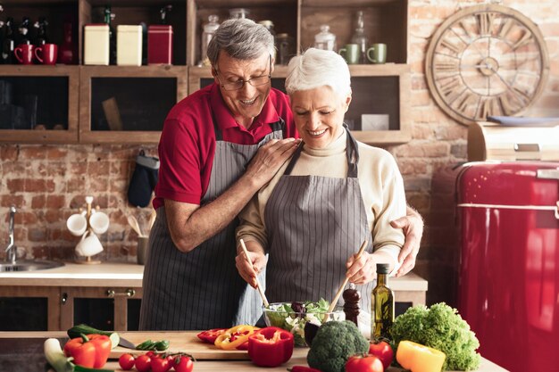 a senior woman with short gray hair wearing a white sweater and a gray striped apron prepares a