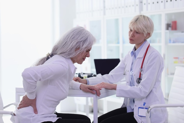 Donna anziana con forte mal di schiena visita la dottoressa nel paziente anziano del gabinetto dell'ospedale