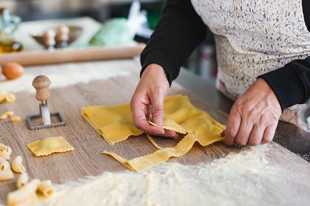 Senior woman working inside pasta factory while doing fresh made ravioli