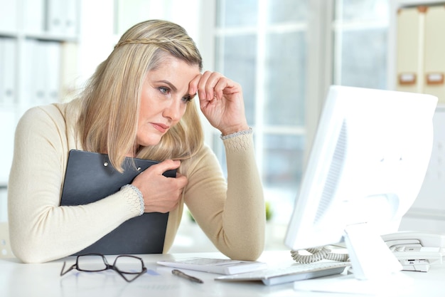 Foto donna anziana che lavora in ufficio con un computer