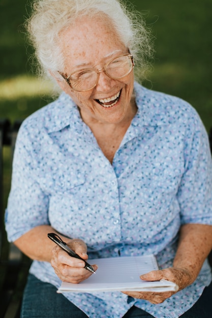 Senior woman writing down her memories into a notebook