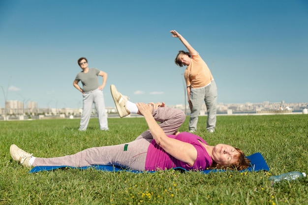 写真 公園の緑の芝生でスポーツトレーニングをしている年配の女性