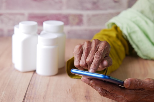 Senior women hand using smart phone and medical pills on table