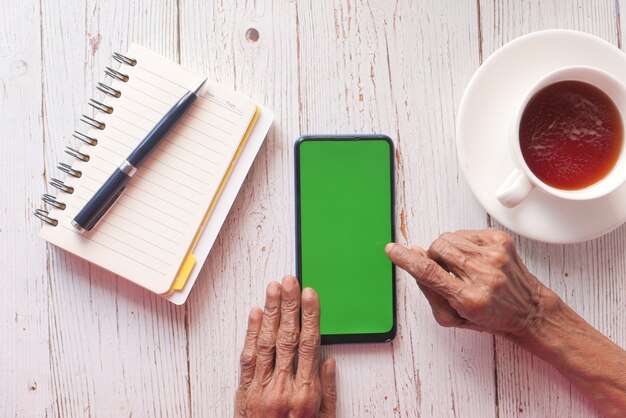 senior women hand using smart phone on table