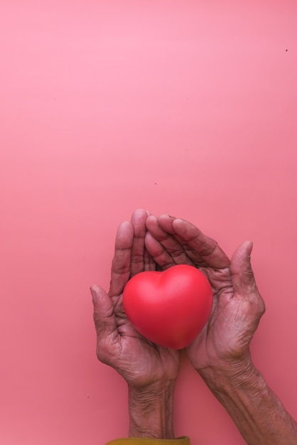 senior women holding red heart in hands