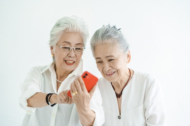 笑顔でスマートフォンの画面を見ている年配の女性