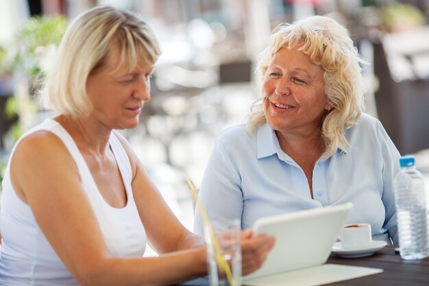 Senior women spending time with pad in outdoor cafe