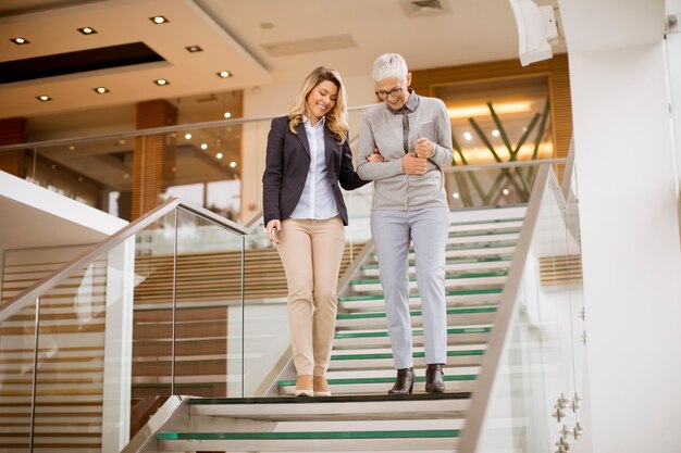 Senior and young businesswomen getting down the stairs