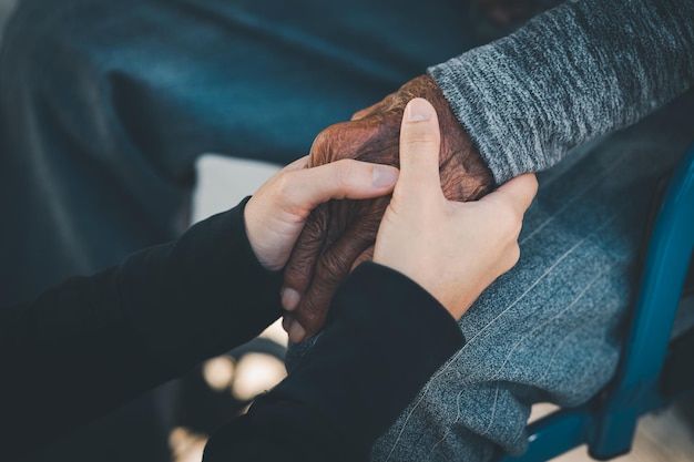 Foto anziane e giovani donne che si tengono per mano amanti della cura