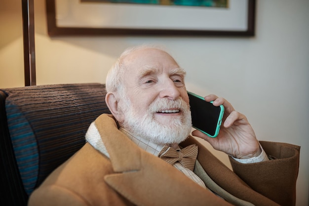 Senior zakenman die aan de telefoon praat en er serieus uitziet