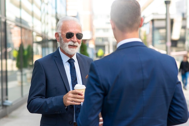 Senior zakenman die iets positiefs bespreekt met zijn jonge collega