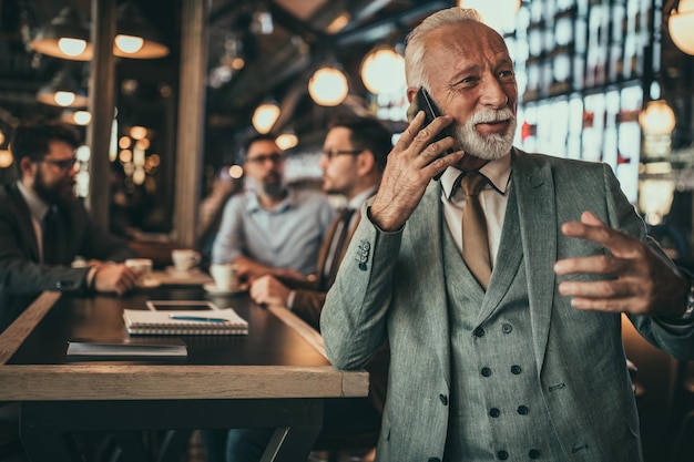 Senior zakenman met behulp van telefoon in de pub