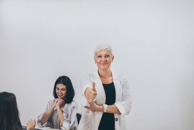 Foto senior zakenvrouw duimen opdagen en werken in office