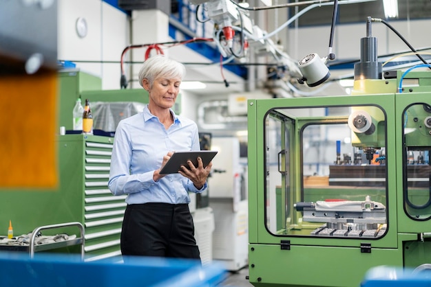 Foto senior zakenvrouw met behulp van tablet in een fabriek