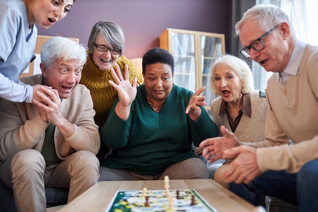 Foto senioren die bordspellen spelen in bejaardentehuis met verbaasde emotie