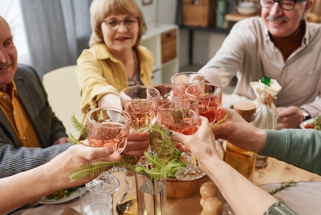 Senioren die rode wijn drinken terwijl ze aan de eettafel zitten en samen een evenement vieren