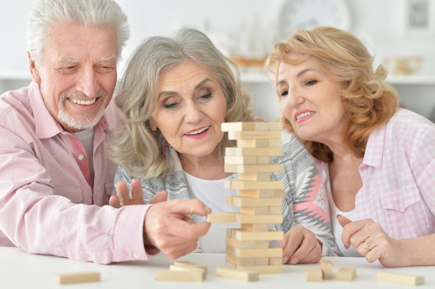 Senioren zitten aan tafel en spelen met houten blokken