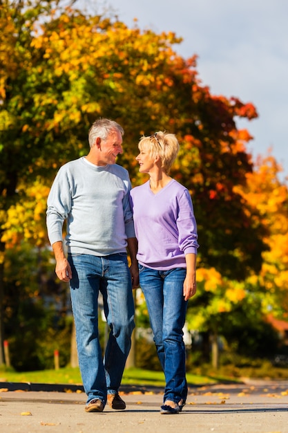 Seniors in autumn or fall walking hand in hand