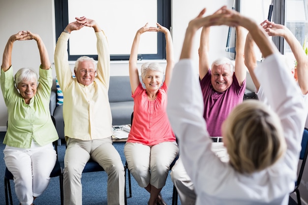 Пожилые люди делают упражнения