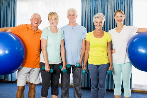 Seniors holding exercise ball and weights