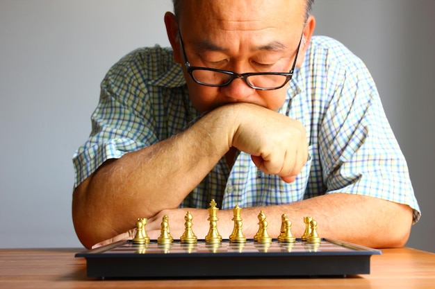 Seniro man looking golden chess pieces on chess game