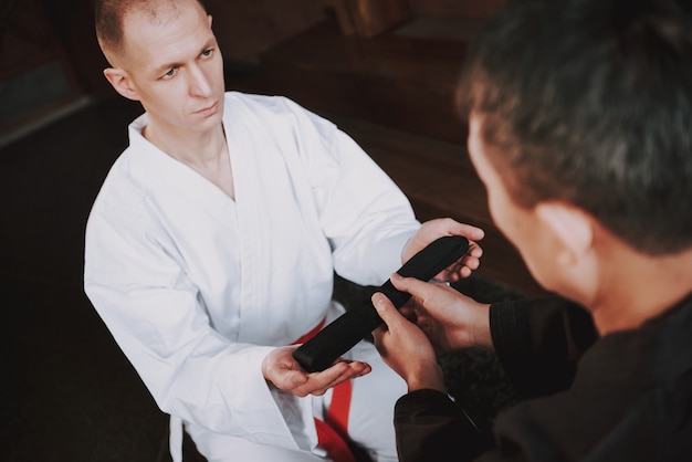 Sensei is giving black belt to martial arts fighter