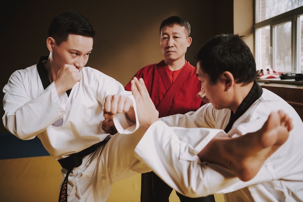 Foto sensei insegna a due studenti di arti marziali a combattere.