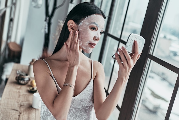 sensitive care for a luminous skin. attractive young woman applying facial mask 